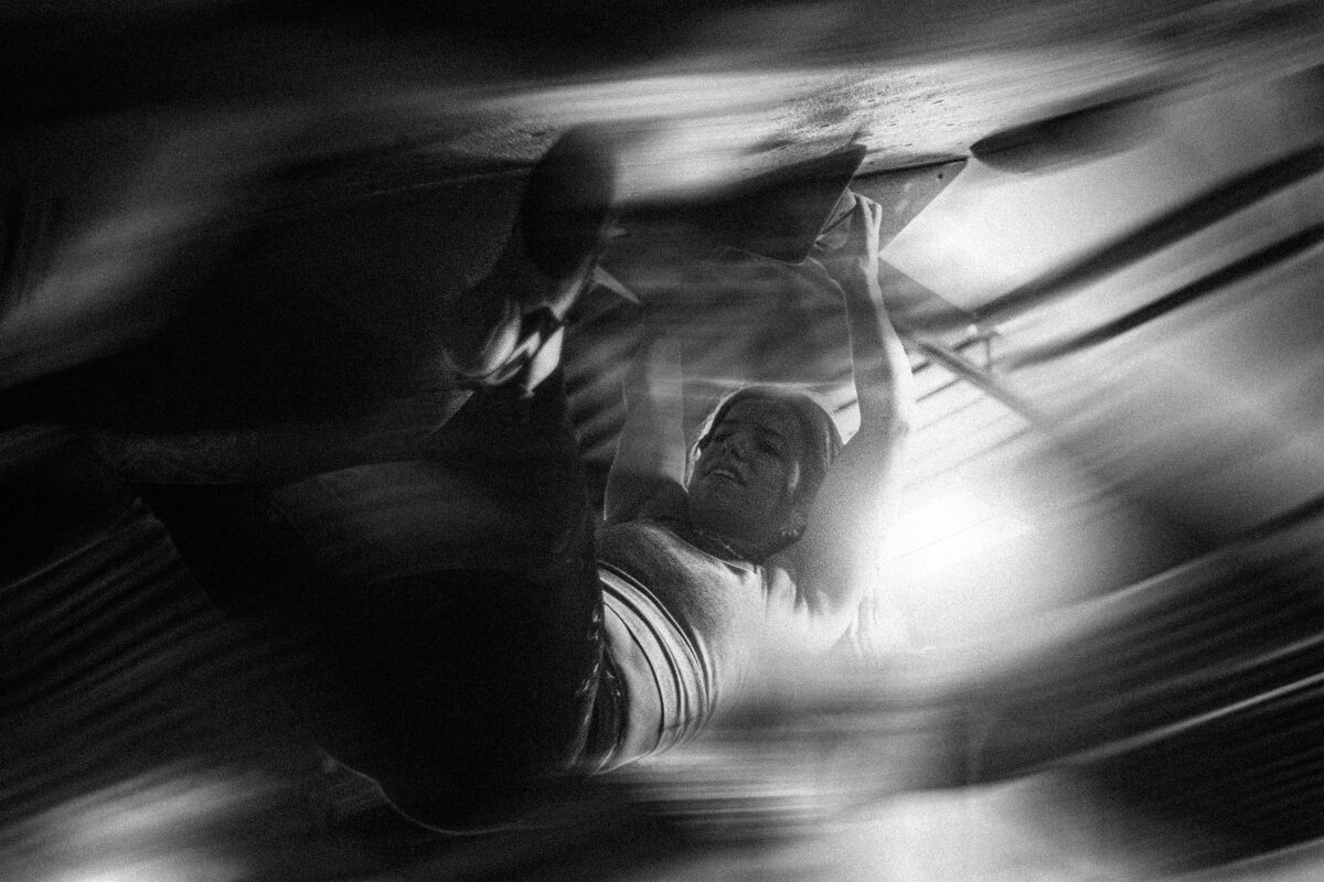 Monochrome image of an individual climbing, viewed from above, with dynamic blur effects emphasizing motion.